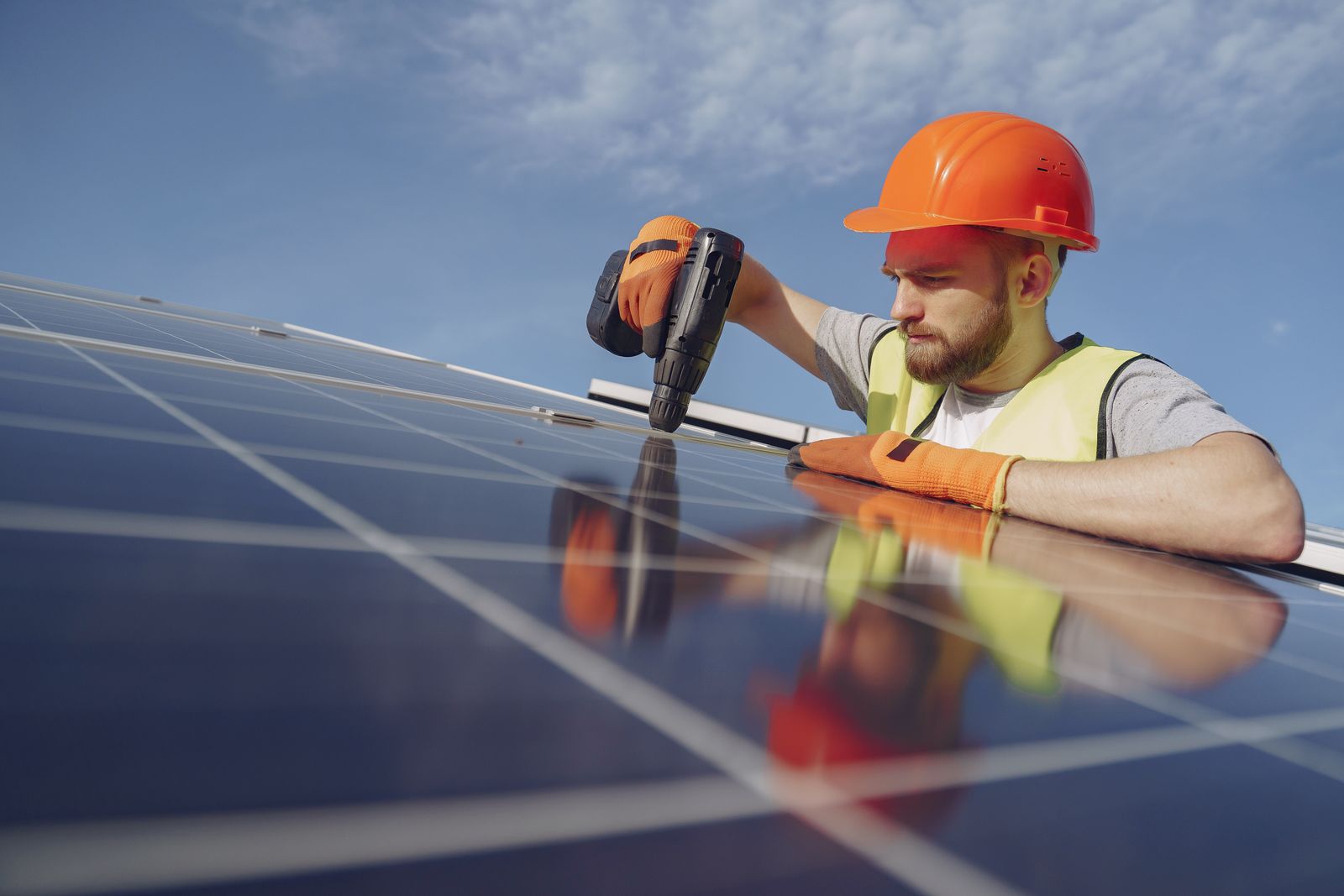 Technician using a drill to fix a solar panel